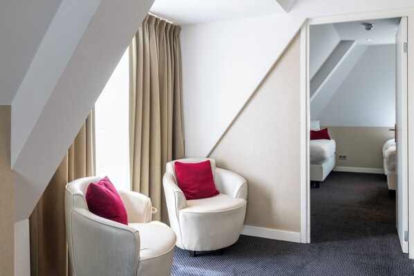 A hotel room with a large window, two armchairs with red cushions, a bed with a red pillow, and a carpeted floor. - Van der Valk Hotel Assen (Assen)