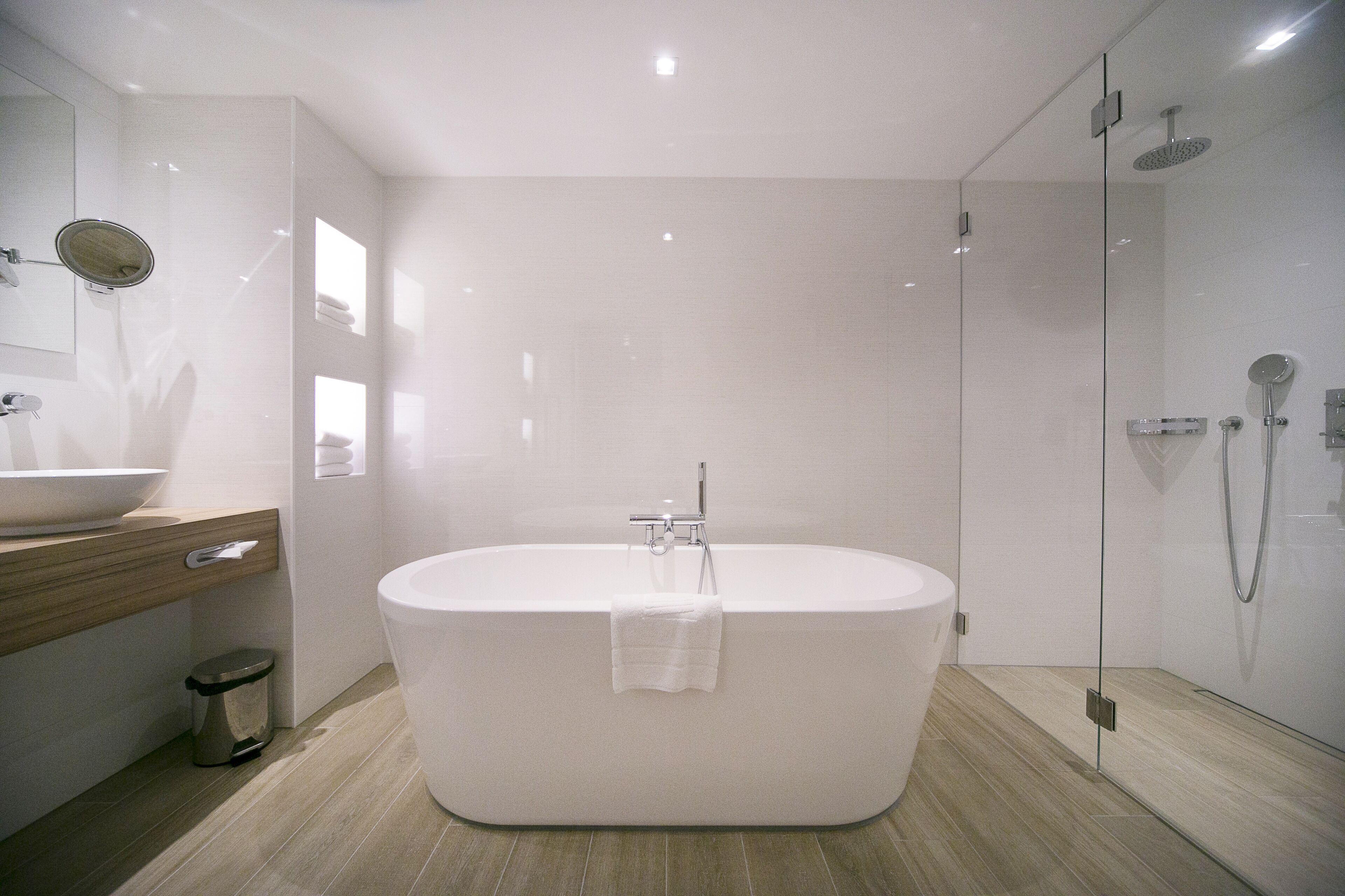 A modern bathroom with a freestanding bathtub, a glass-enclosed shower, and a wooden vanity with a sink.