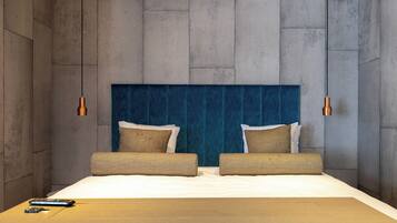 Una habitación de hotel moderna con una cama grande, dos mesitas de noche y un cabecero azul.