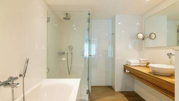 A modern bathroom with a glass-enclosed shower, a white bathtub, and a wooden vanity with a sink.
