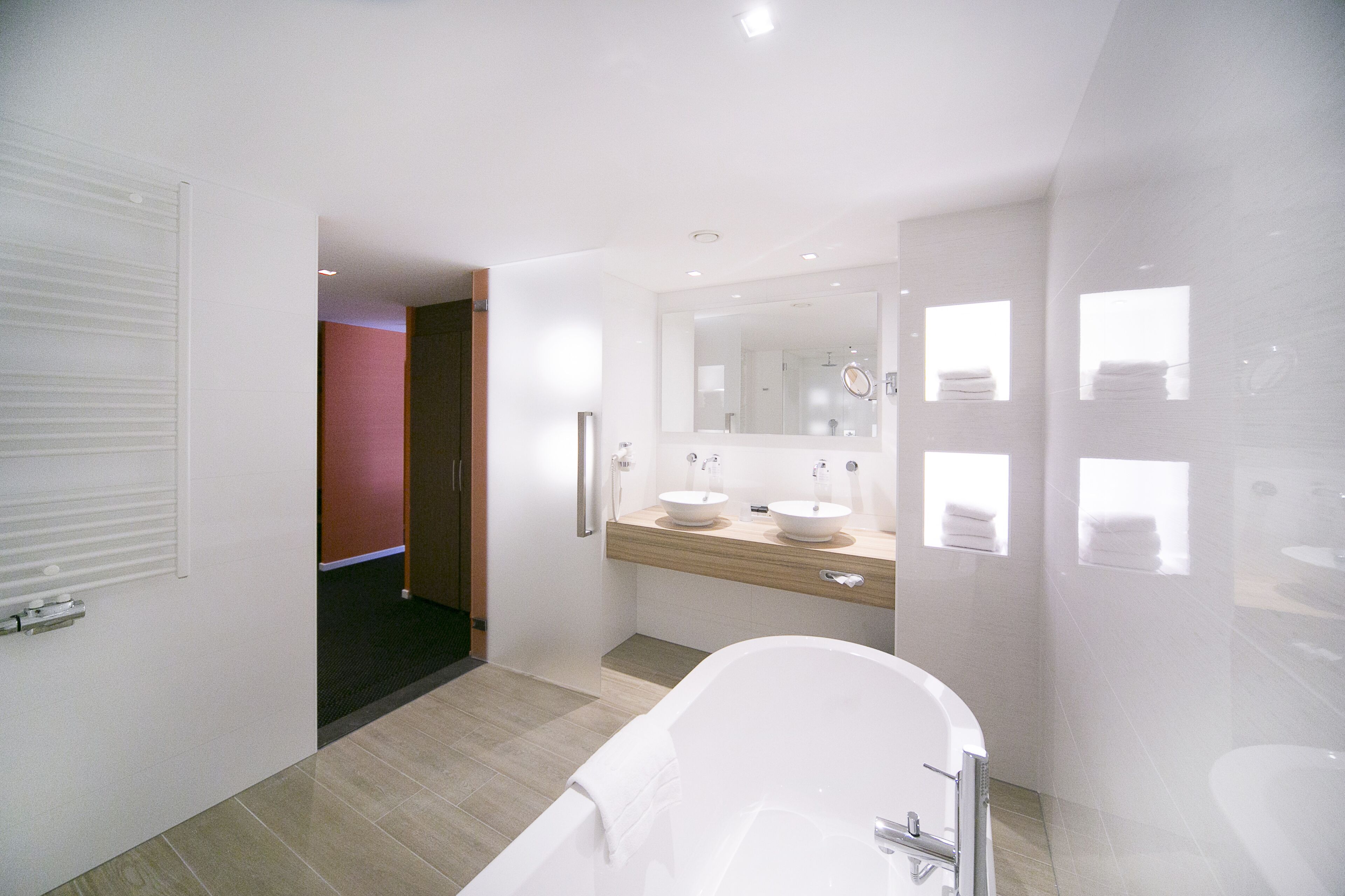 A modern bathroom with a freestanding bathtub, a double sink vanity, and a large mirror.