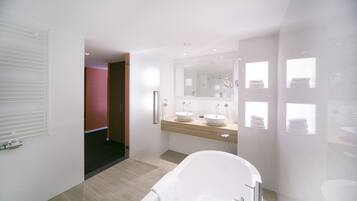 Un baño moderno con una bañera independiente, un tocador doble y un espejo grande.