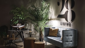 A modern living room with a grey sofa, a coffee table, a side table, and a large potted plant. - Van der Valk Hotel Assen (Assen)