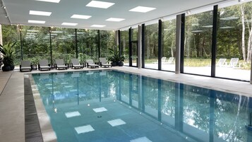 Una piscina techada, sillones reclinables de piscina