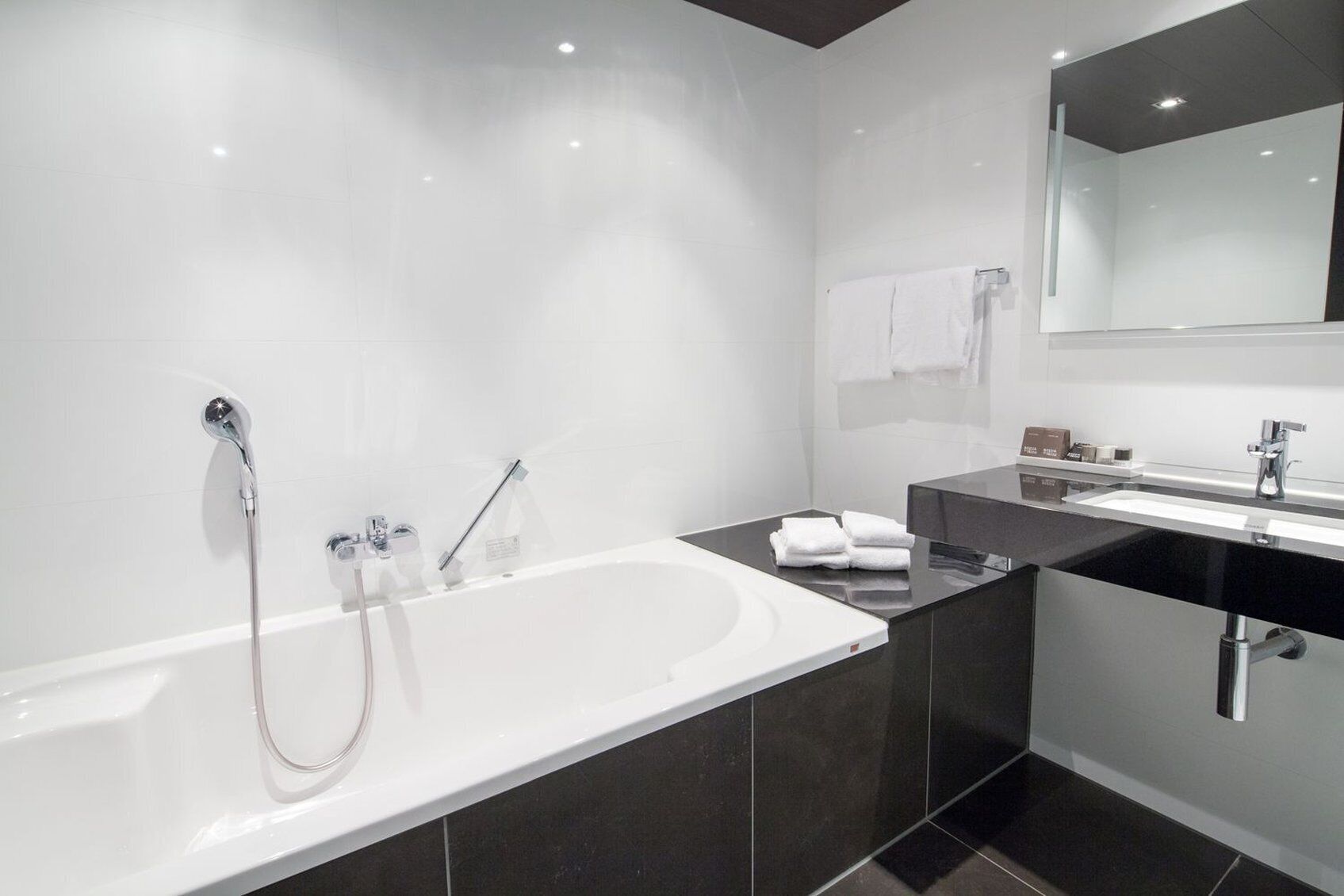 Un baño moderno con una bañera grande, zona de ducha separada y tocador con espejo.