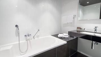 Un baño moderno con una bañera grande, zona de ducha separada y tocador con espejo.