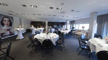 A hotel dining area with round tables, black chairs, and white tablecloths.