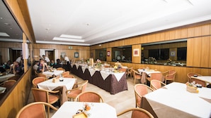 Ein Restaurant mit mehreren Tischen und Stühlen, Holzwandverkleidung und einer Theke in der Mitte.