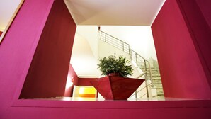Ein modernes Interieur mit roter Akzentwand, einem Blumentopf und einer Treppe.