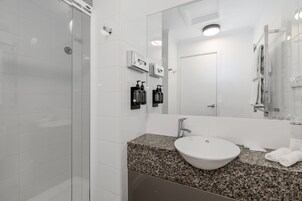 A modern bathroom with a granite countertop, a white sink, and a large mirror.