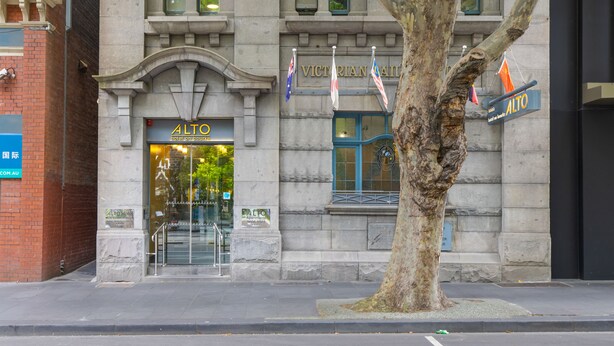 Fachada de hotel con el nombre 'ALTO' y banderas, incluyendo la bandera australiana.
