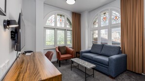 Una sala moderna con un escritorio de madera, un sofá azul, un sillón marrón y una pequeña mesa de centro.