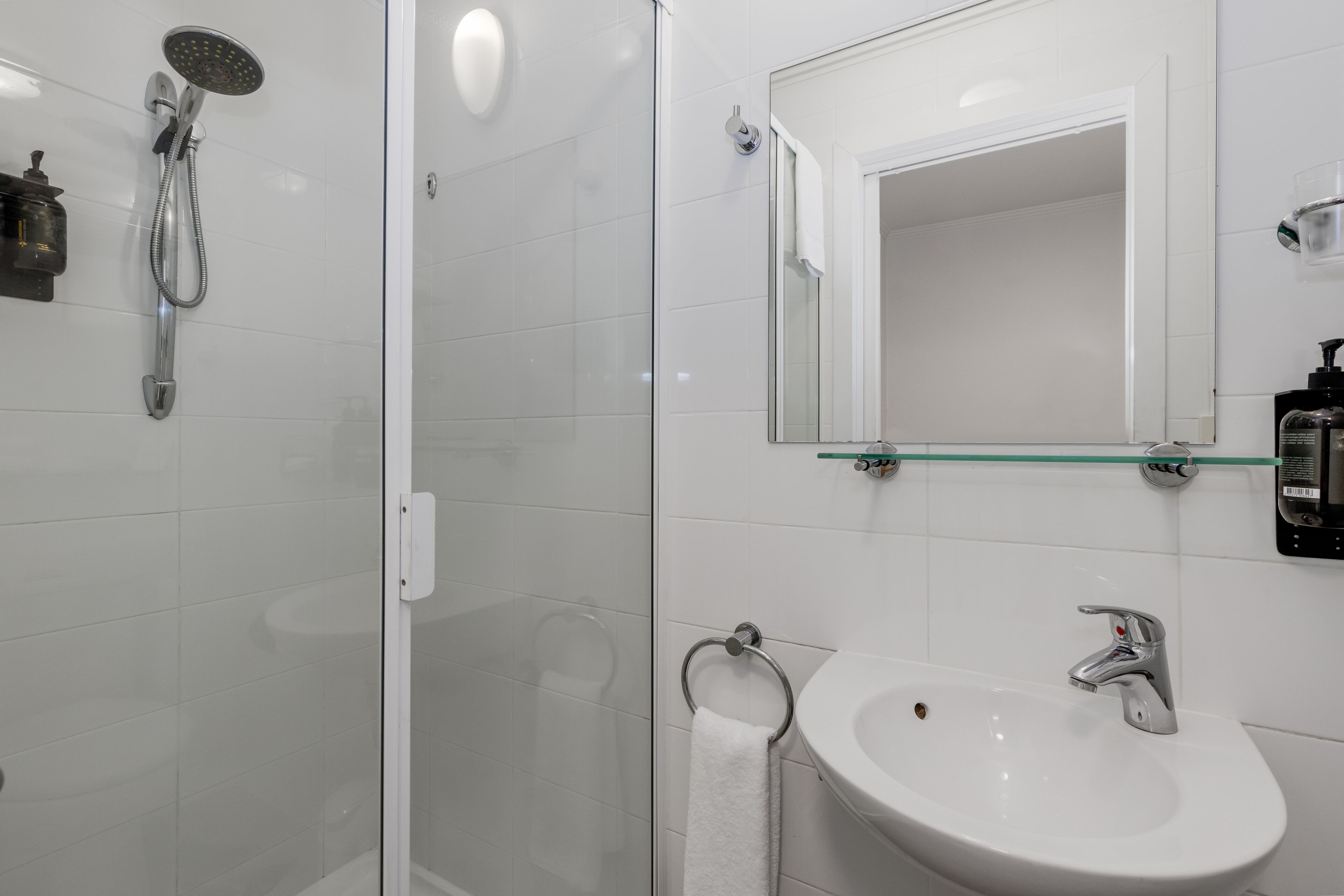 A modern bathroom with a glass-enclosed shower, a white sink, and a mirror above the sink.