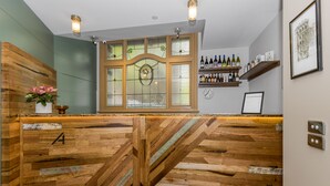 Un mostrador de recepción de madera con un amplio ventanal, un reloj de pared y estantes con botellas de vino.
