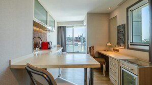 A compact kitchen with a dining area, a large window offering a city view, and a kitchenette with a microwave and coffee maker. - Ramada by Wyndham Ankara (Ankara)