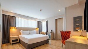 A modern hotel room with a large bed, a desk, a chair, and a small table with a lamp. - Ramada by Wyndham Ankara (Ankara)