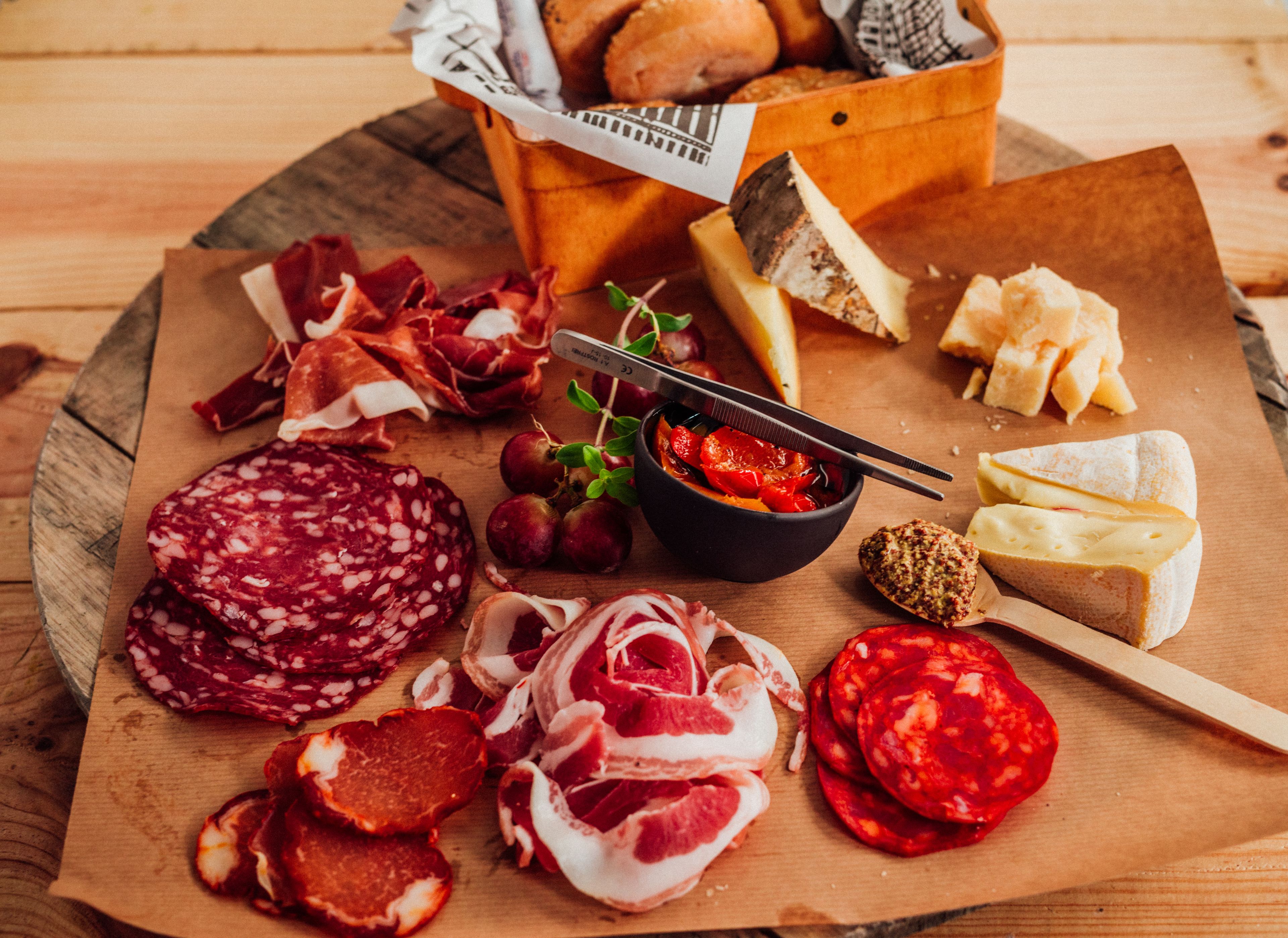 A wooden board with various cured meats, cheeses, and bread.
