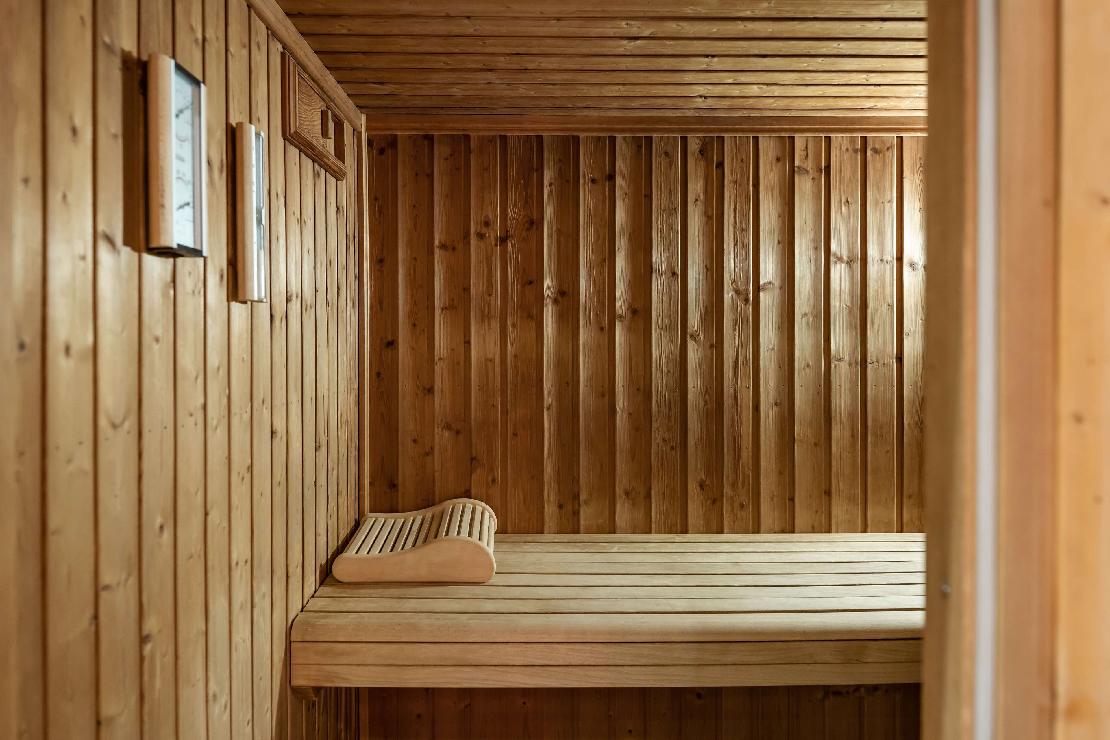 Una sauna de madera con un banco e iluminación en la pared.