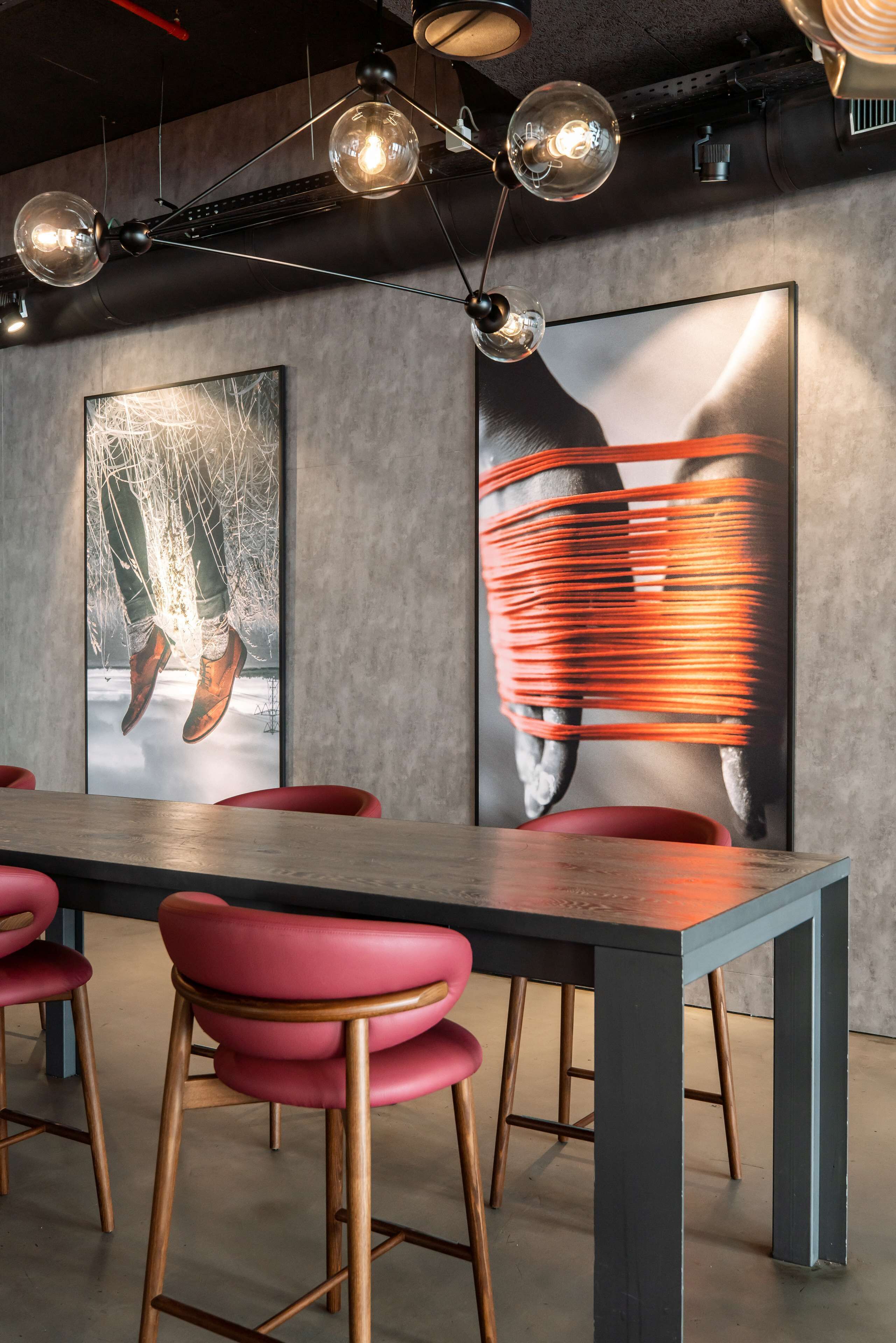 Un salón de conferencias con una larga mesa, sillas rojas e iluminación colgante moderna.