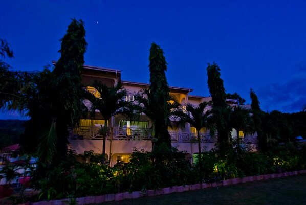 A multi-story hotel with balconies, surrounded by lush greenery.