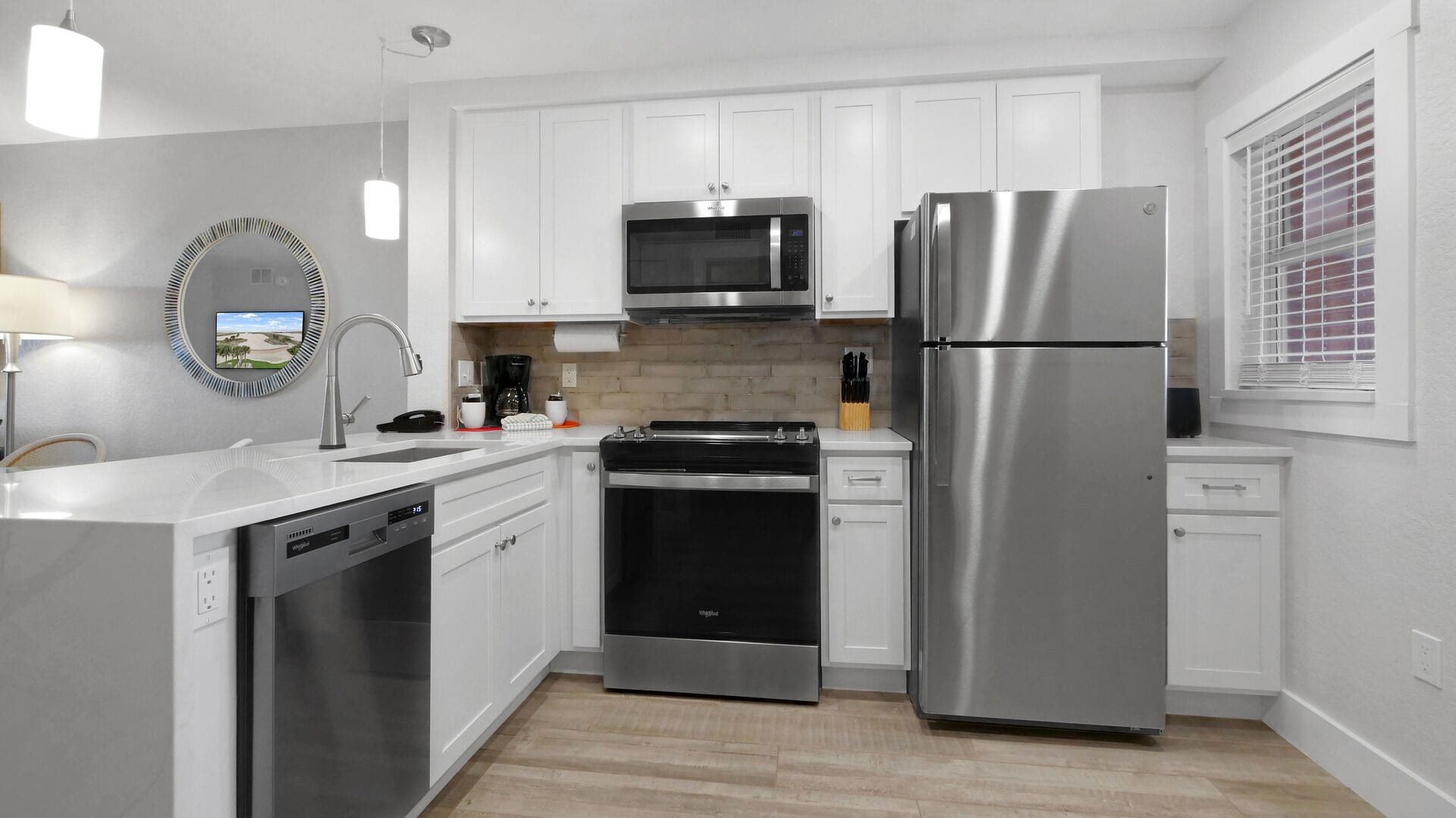 A modern kitchen with white cabinets, stainless steel appliances, a dishwasher, and a built-in oven.