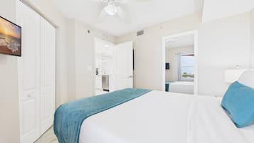 Een hotelkamer met een bed, een plafondventilator, een raam met uitzicht en een deur naar een badkamer.