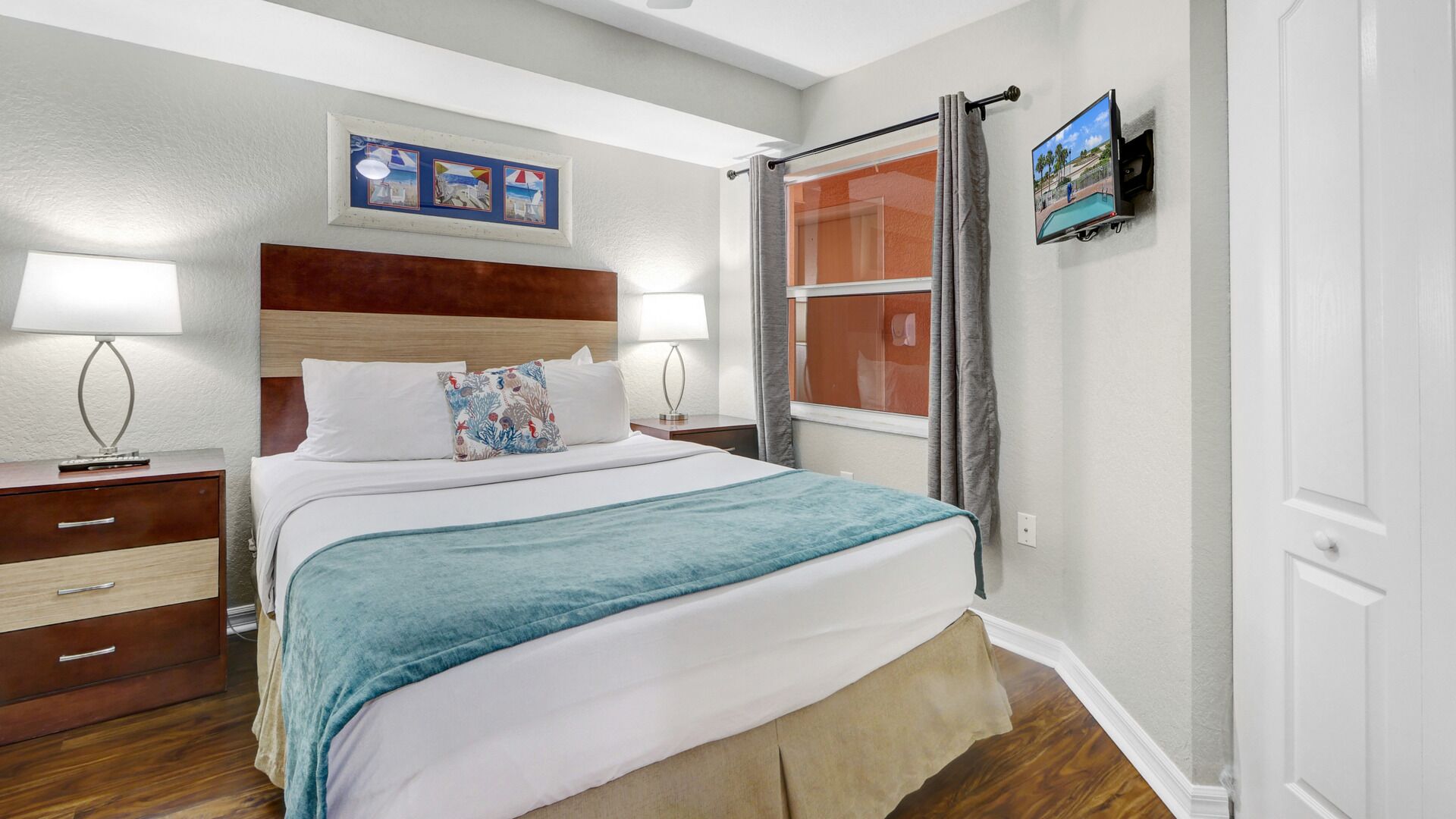 A neatly arranged hotel room with a bed, bedside tables, a TV, and a window with curtains.