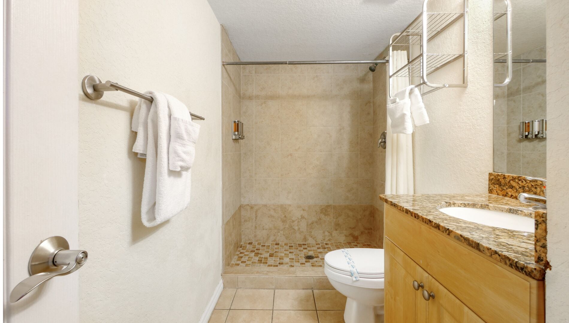 Ein Badezimmer mit Dusche, Toilette und Waschtisch mit Spiegel.