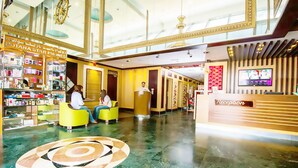 Un vestíbulo de hotel con una recepción, zonas de estar y una tienda llamada "KOTANA STAR PHONES".