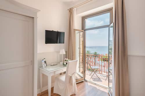Habitación doble, vista al mar | Edredón, minibar, caja de seguridad en la habitación y escritorio