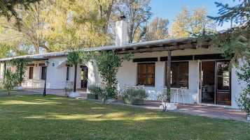 A white building with a covered patio, outdoor seating, and potted plants.