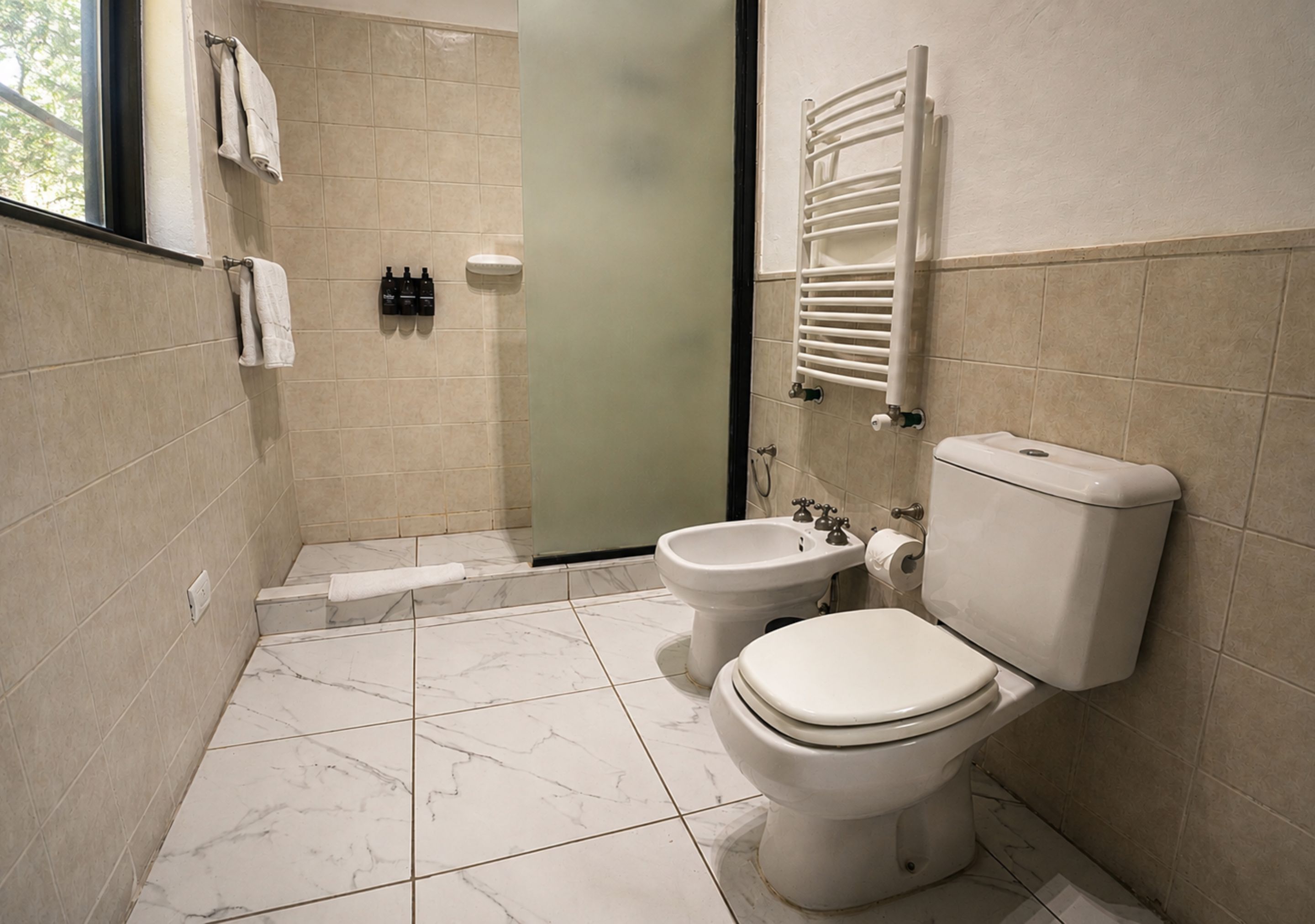 A bathroom with a toilet, bidet, and towel rack.