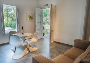 A modern interior with a dining area, a sofa, and a door leading to an outdoor garden. - Postales Finca & Bodega by DOT Boutique (Tunuyan)