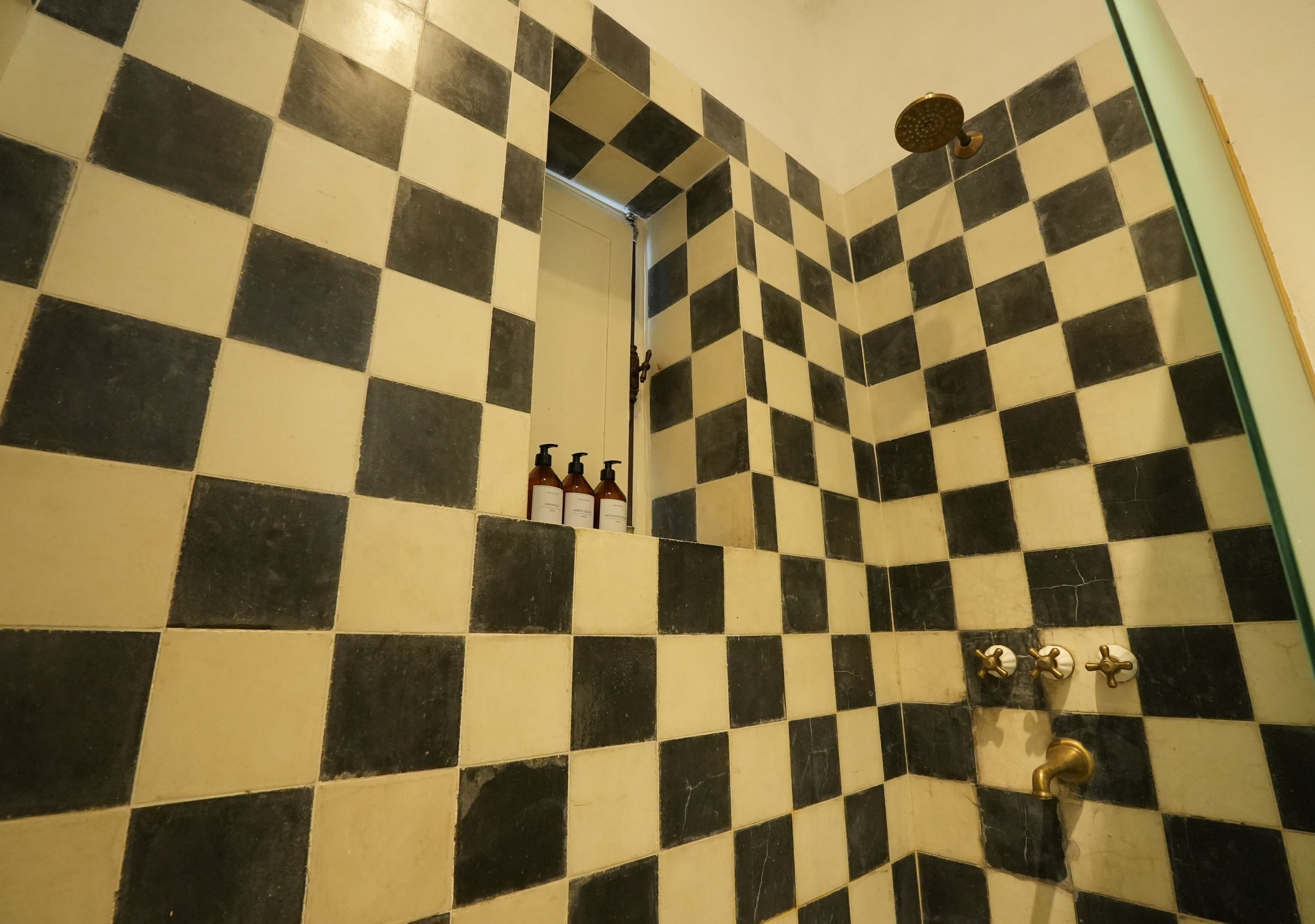 Un bagno con piastrelle bianche e nere a scacchi, una zona doccia e uno scaffale con articoli da toilette.