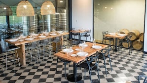 A restaurant interior with checkered flooring, multiple tables set for dining, hanging wicker lamps, and stainless steel tanks in the background. - Postales Finca & Bodega by DOT Boutique (Tunuyan)