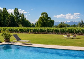 A swimming pool with lounge chairs and a view of mountains. - Postales Finca & Bodega by DOT Boutique (Tunuyan)
