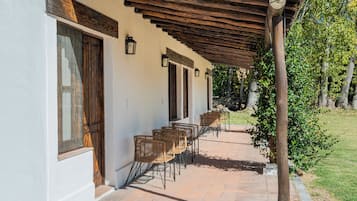 Ein überdachter Außenbereich mit Stühlen und Tischen, Holztüren und einer Pergola.