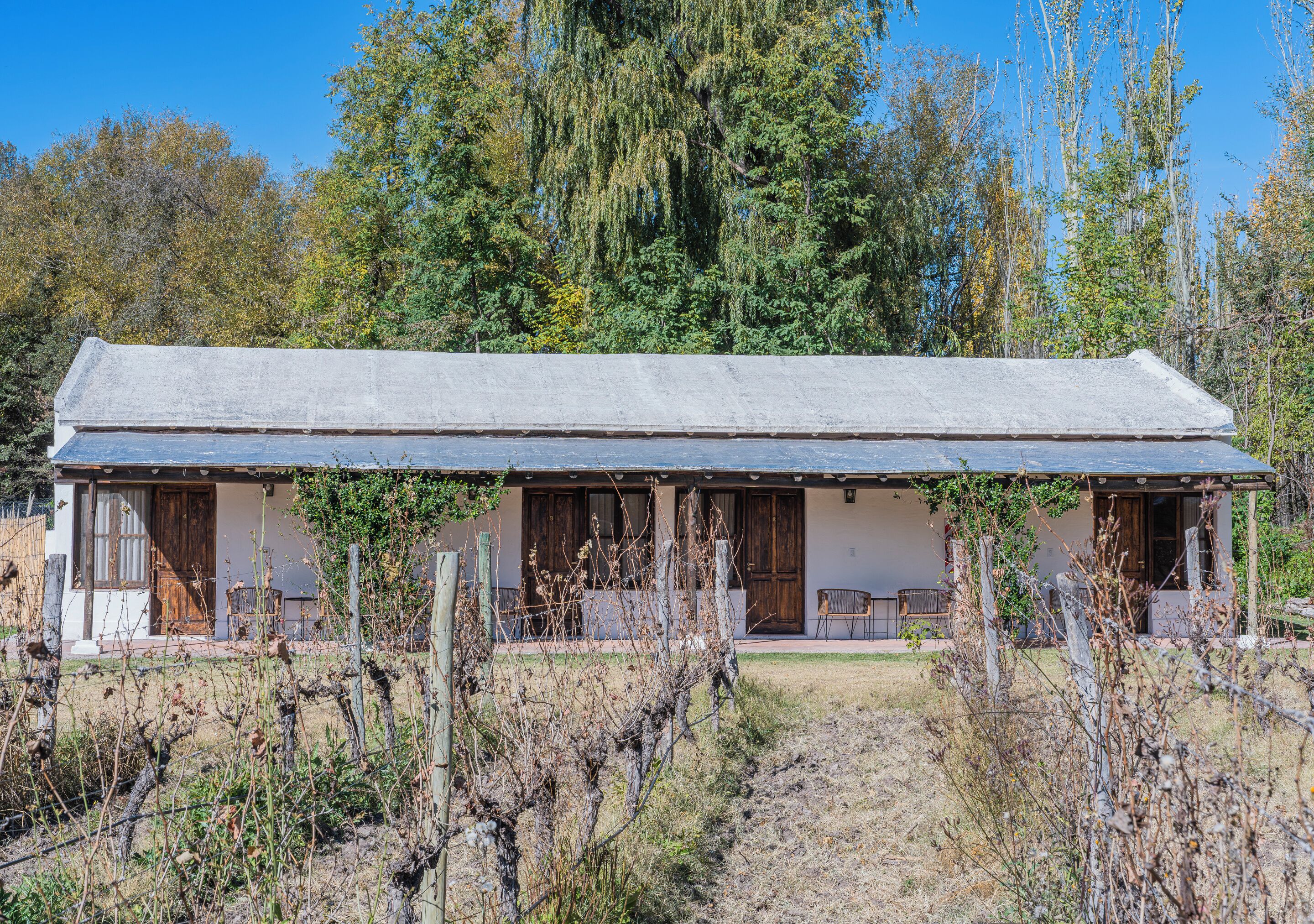 Eine rustikale Holzhütte mit einer langen Veranda, Holztüren und einem umzäunten Garten.