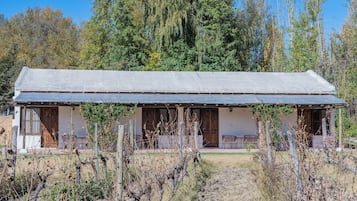 Eine rustikale Holzhütte mit einer langen Veranda, Holztüren und einem umzäunten Garten.
