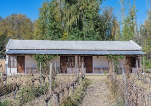 A rustic cabin with a long porch, wooden doors, and a fenced yard. - Postales Finca & Bodega by DOT Boutique (Tunuyan)