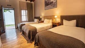 A hotel room with three beds, wooden flooring, a door labeled 'SALIDA,' and a framed picture on the wall. - Postales Finca & Bodega by DOT Boutique (Tunuyan)