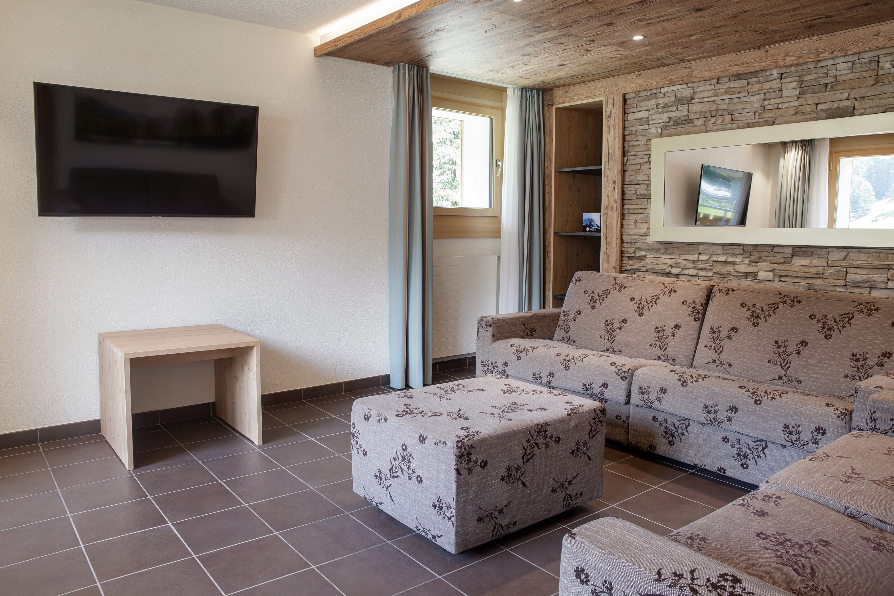 A living room with a sofa, ottoman, and a small wooden table.