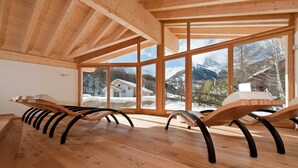 Una habitación con vigas de madera, ventanas amplias y sillones reclinables.