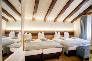 A hotel room with two beds, wooden beams on the ceiling, and a view of the sea.