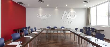 A conference room with a long table, blue chairs, and a red accent wall.