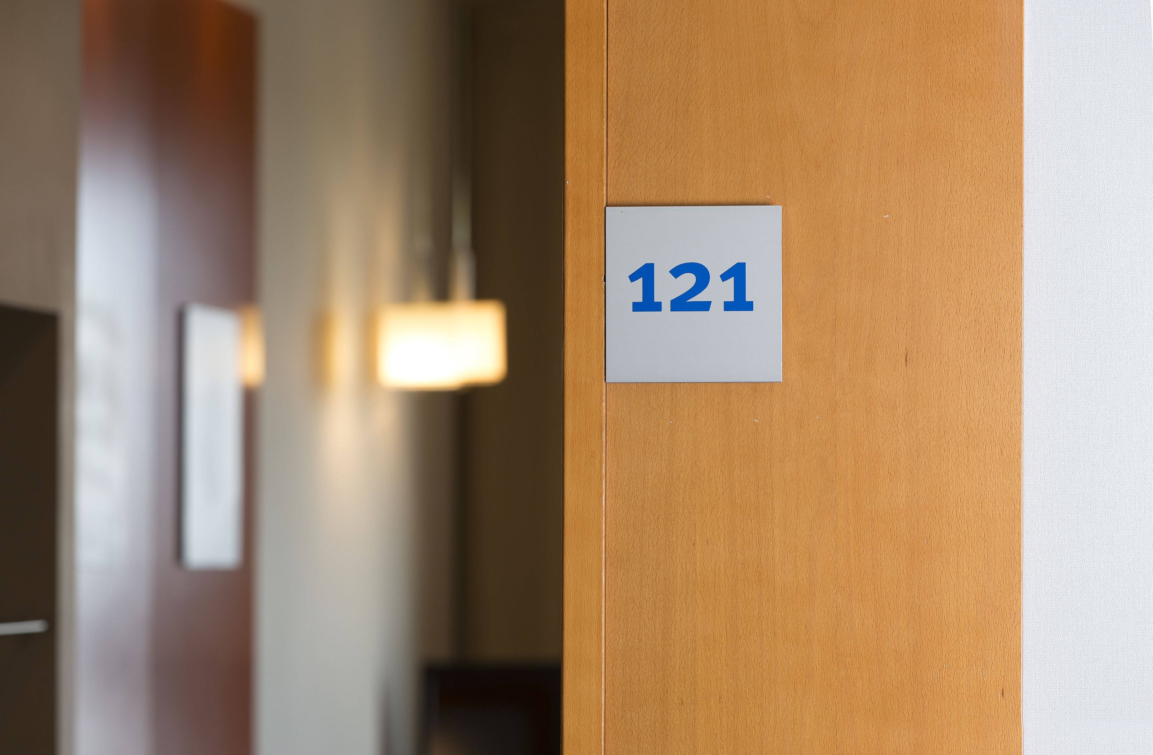 A hallway with a sign indicating room number 121.