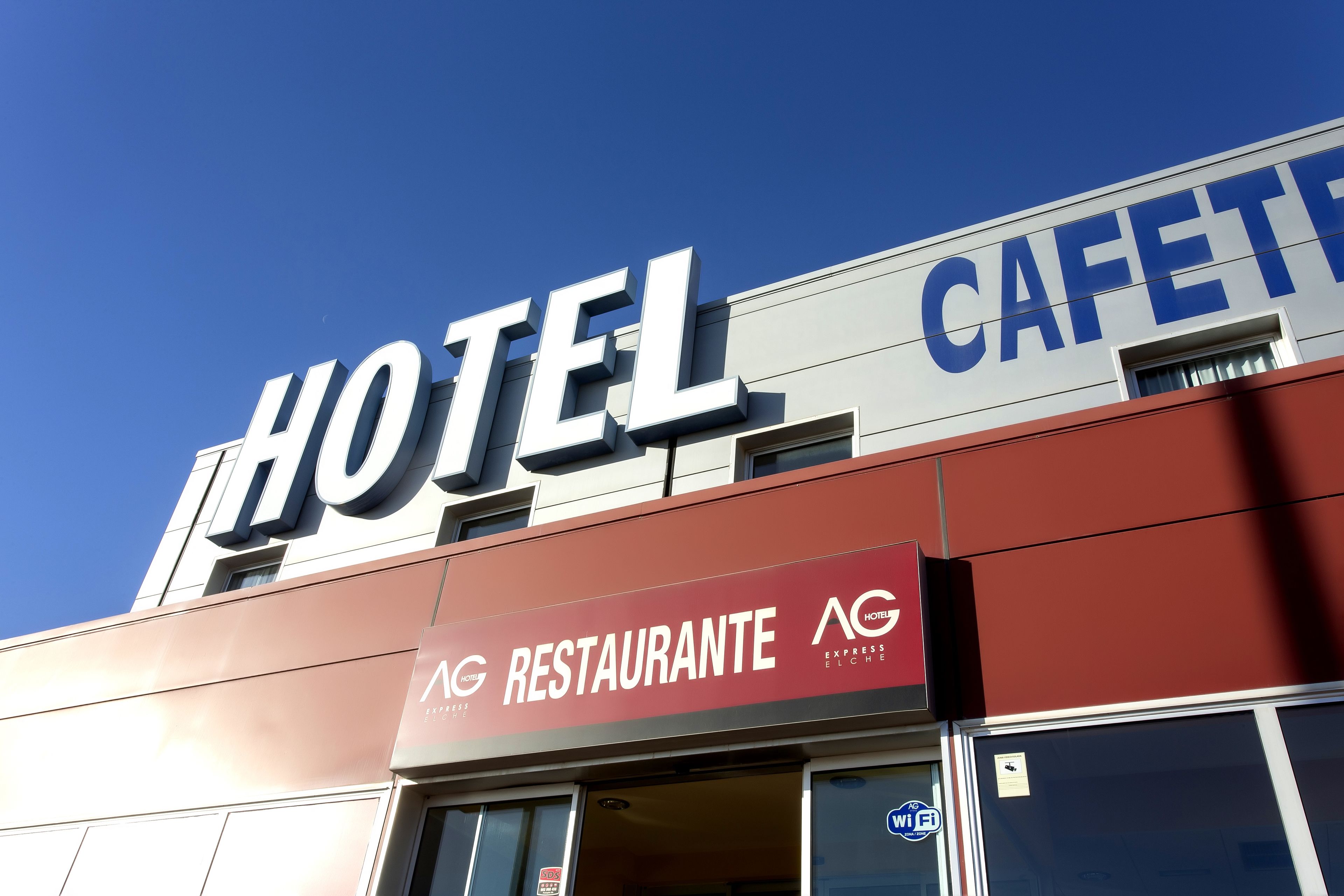 A hotel with a prominent 'HOTEL' sign and a 'RESTAURANTE' sign below it.