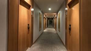 A long, narrow hotel corridor with wooden doors on both sides, leading to individual rooms. - Hotel AG Express Elche (Elche)