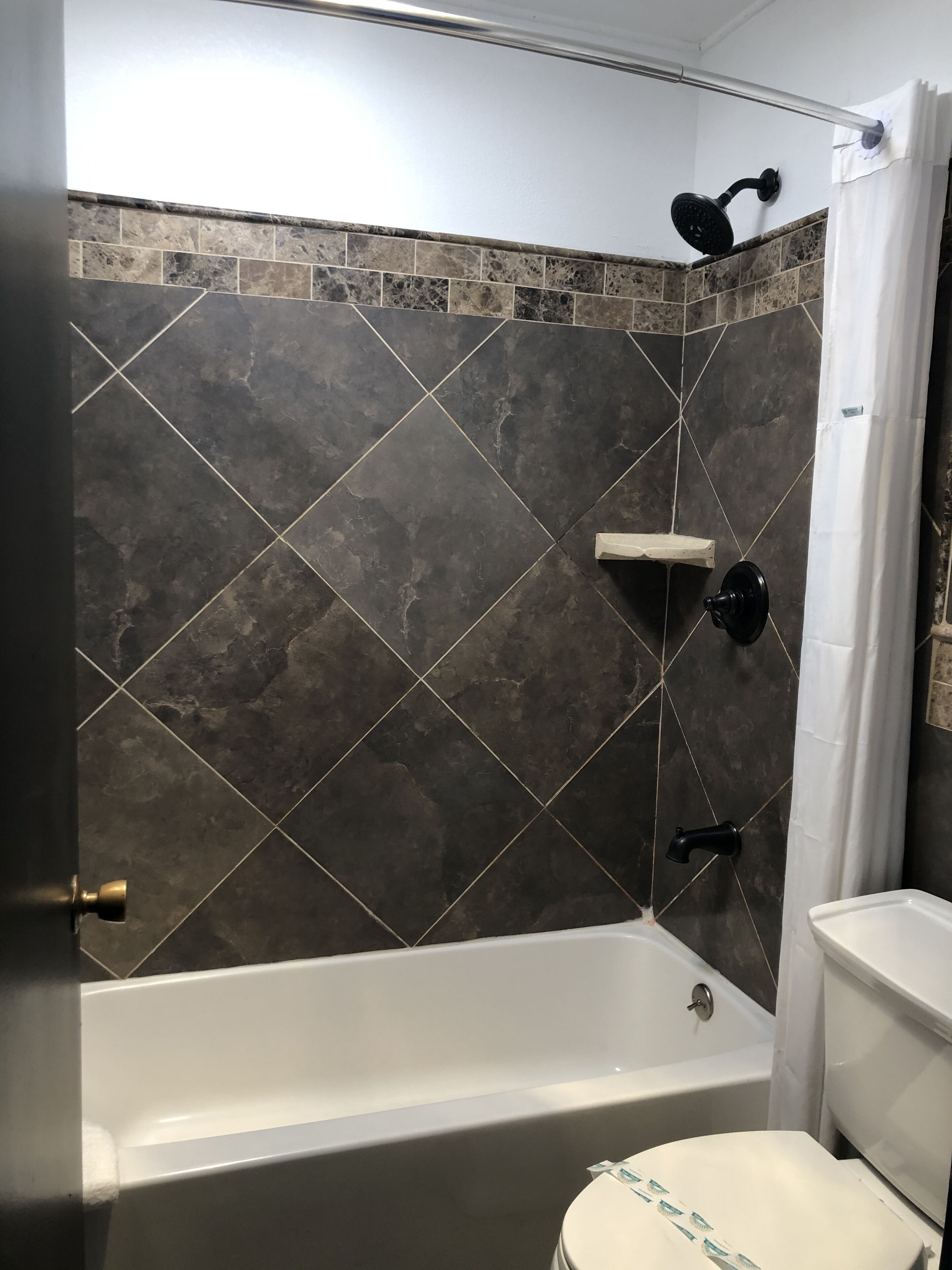 Een badkamer met een bad, douche en toilet.
