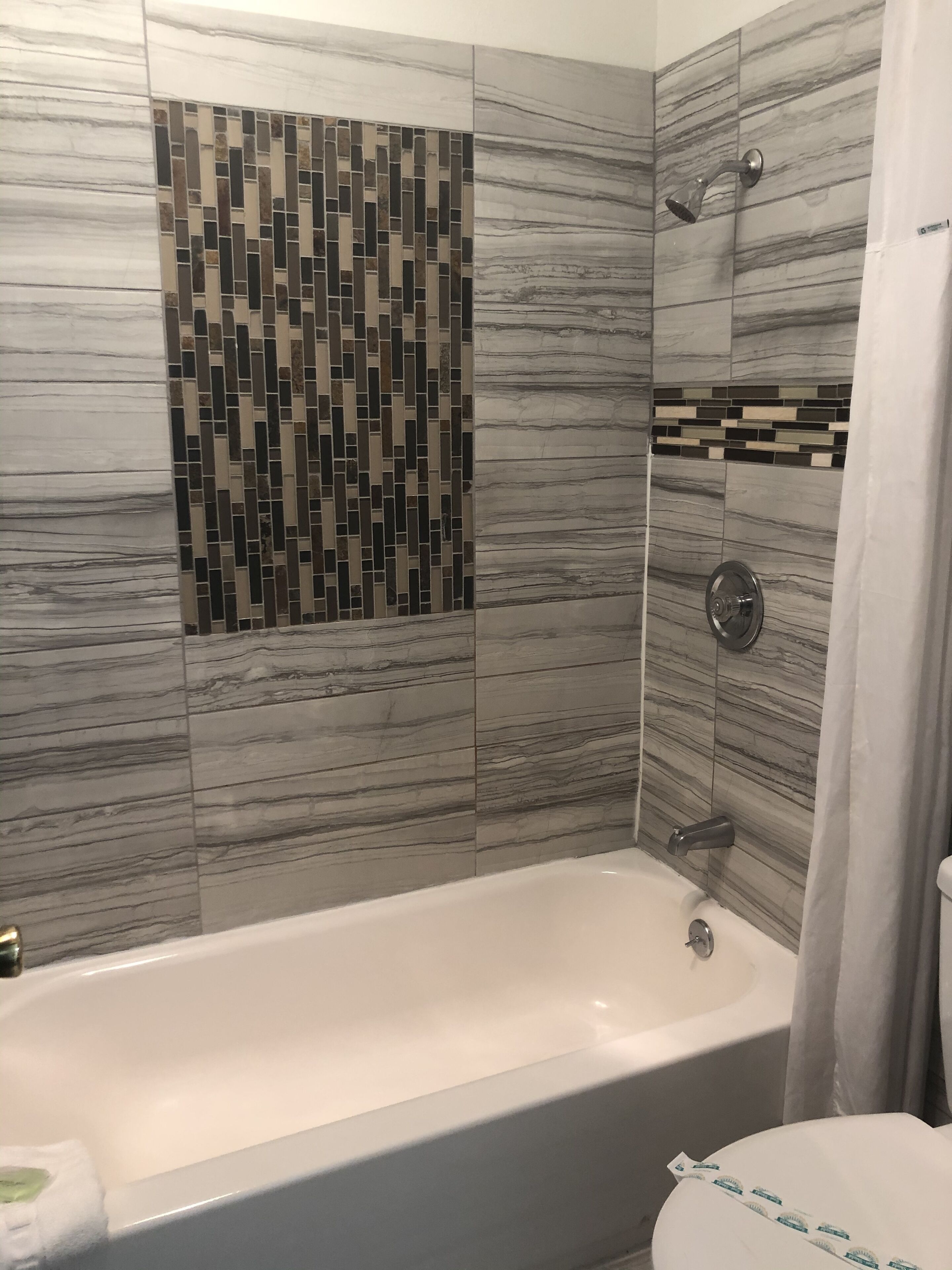 A bathroom with a bathtub, shower, and tiled walls.